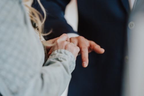 Eine Frau steckt einem Mann einen Ehering an.