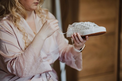 Eine Frau hält einen Brautschuh in der Hand.