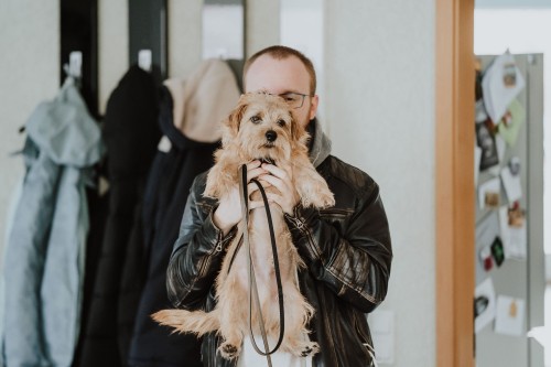 Ein Mann hält einen Hund hoch.
