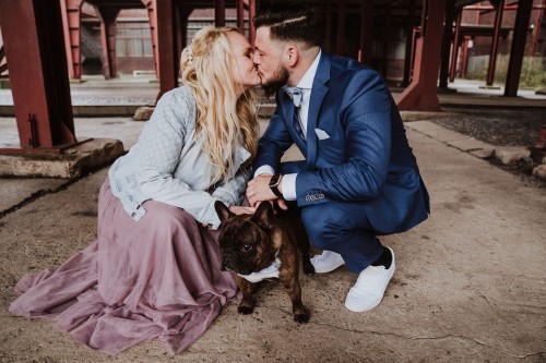 Ein Brautpaar küsst sich und zwischen den beiden steht ein Hund.