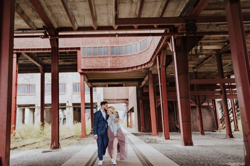 Ein Brautpaar spaziert umarmt durch das Gelände der Zeche Zollverein.