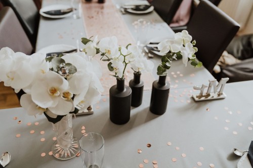 Festlich gedeckter Tisch mit Orchideen in den Blumenvasen.