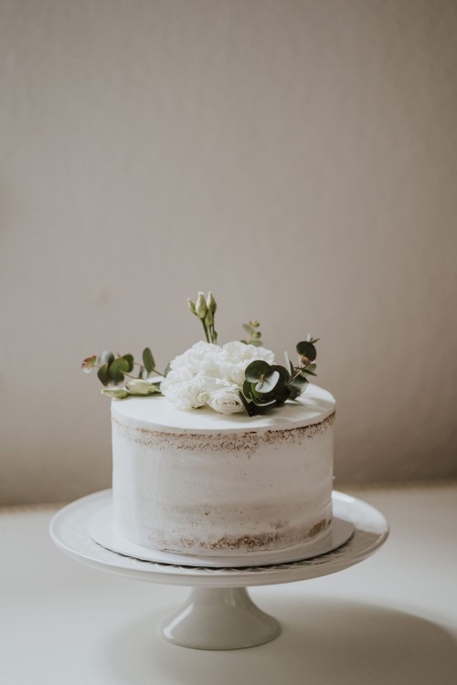 Eine weiße Torte mit Blumen Deko drauf.