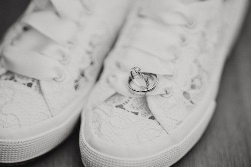 Ein schwarz-weißes Bild von Brautschuhen und liegenden drauf Ringen.