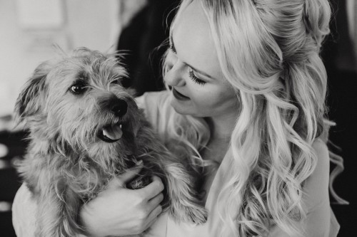 Eine Braut hält einen Hund auf dem Arm.
