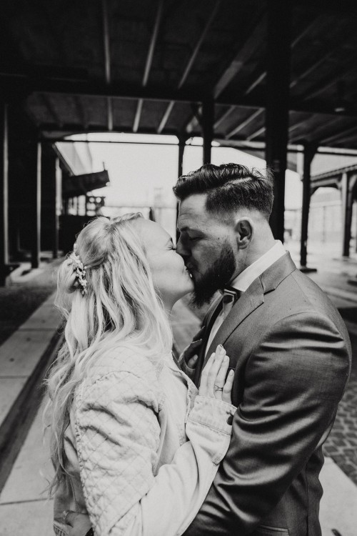 Ein schwarz-weißes Bild von einem küssendem Brautpaar.