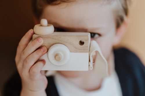 Eun Kind spielt mit einer Holzkamera.
