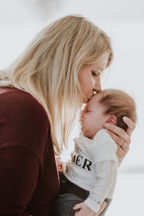 Eine Frau küsst ein Baby an der Stirn.