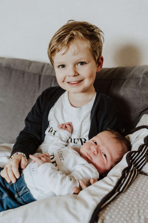 Ein Baby wird festgehalten von einem größerem Kind.