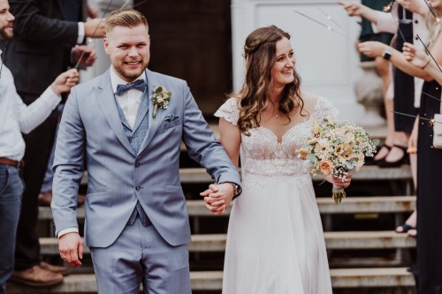 Eine Braut und ein Bräutigam ziehen aus dem Standesamt aus.