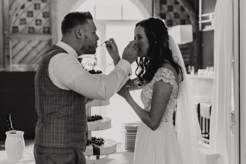 Eine Braut und ein Bräutigam füttern sich gegenseitig mit der Hochzeitstorte.