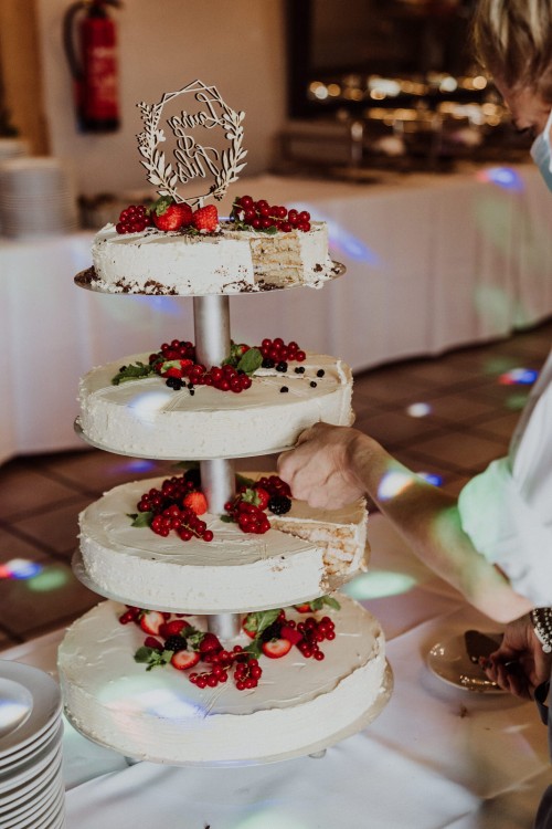 Eine mehrstöckige Hochzeitstorte mit Beeren drauf.