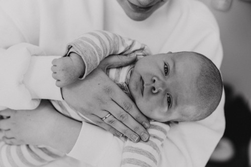 Ein Baby wird von einer Frau auf dem Arm gehalten.