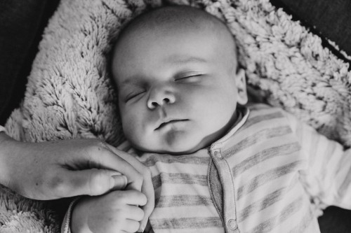 Ein Baby schläft und hält Mamas Hand