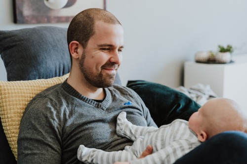 Ein Mann hält ein Baby auf seinem Schoß.