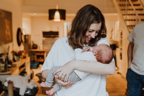 Eine Frau hält ein Baby im Arm und schaut es liebevoll an.