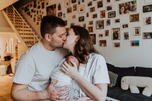 Eine Frau und ein Mann küssen sich während sie ein Baby hält.