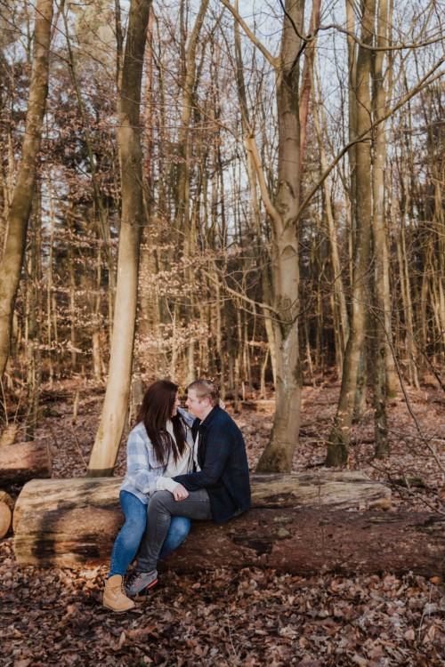 Eine Frau und ein Mann sitzen auf einem umgefallenem Baumstamm.