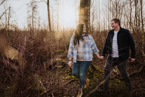 Eine Frau und ein Mann gehen durch einen Wald und halten Händchen.