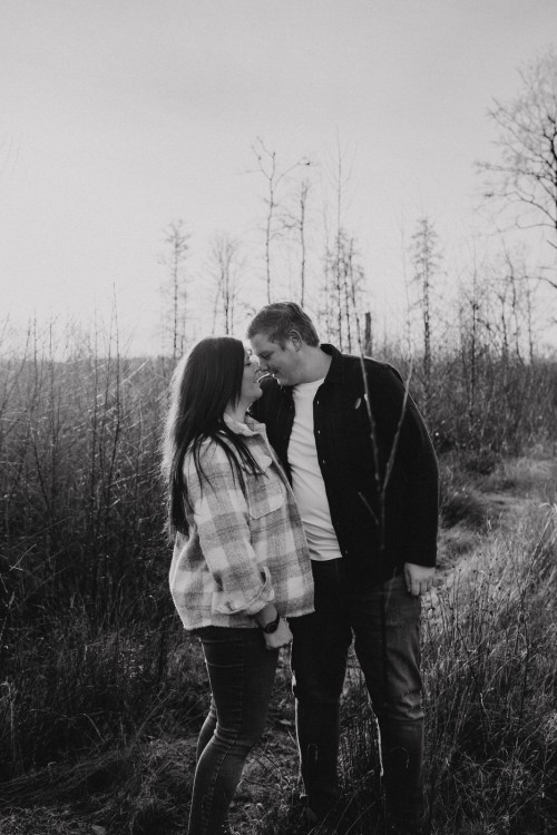 Eine Frau und ein Mann stehen sich ganz nah auf einem Waldweg.