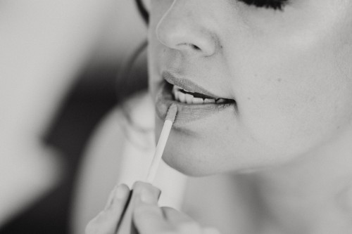 Eine Frau schminkt einer Braut die Lippen.