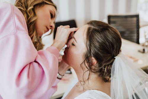 Eine Frau schminkt eine Braut.
