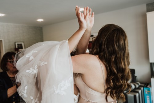 Eine Braut zieht ihr Brautkleid an.