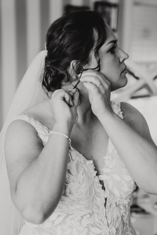 Eine Braut zieht ihre Ohrringe an.