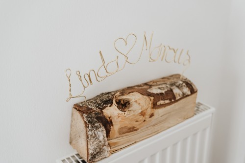 Holzscheit mit einem Schriftzug aus Draht.