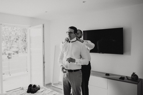 Ein Mann richtet dem Bräutigam seine Fliege.