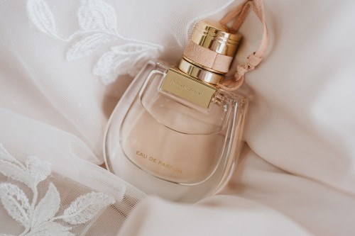 Ein Parfüm Flakon auf einem bestickten Stoff.