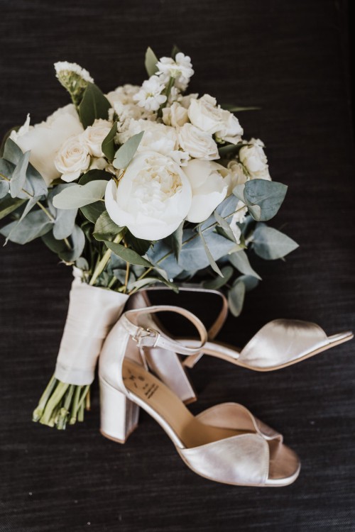 Blumenstrauß und Schuhe liegen auf einem Tisch