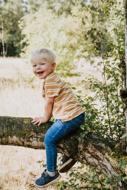 Ein kleiner Junge sitzt auf einem Ast.
