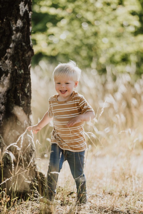 Ein kleiner Junge rennt durch eine Wiese.