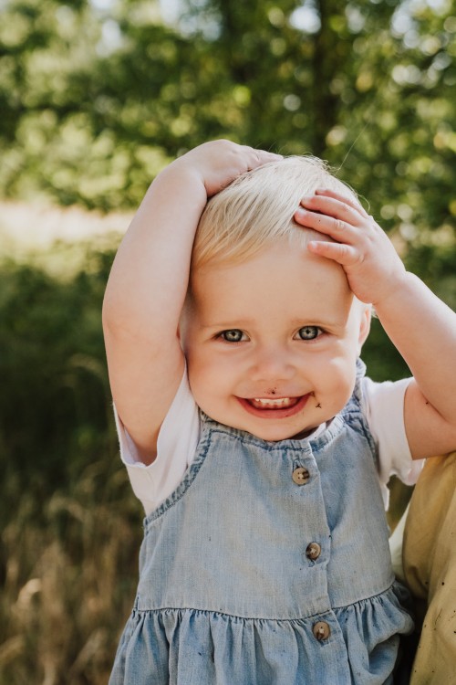 Ein kleines Mädchen hält ihre Hände über ihrem Kopf.