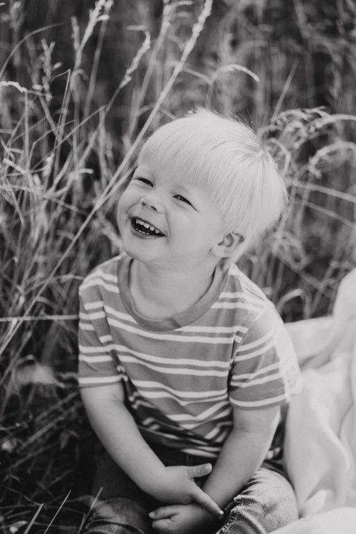 Ein kleiner Junge sitzt auf einer Wiese.