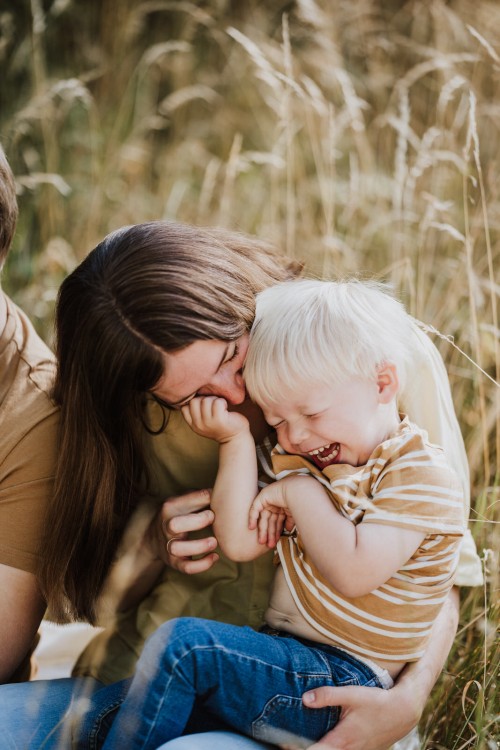 Eine Frau kitzelt ein kleines Kind.