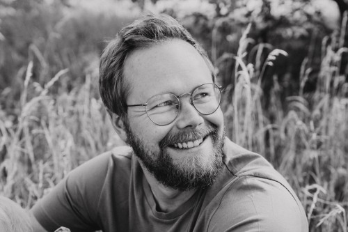 Ein Mann mit einer Brille auf einer Wiese.