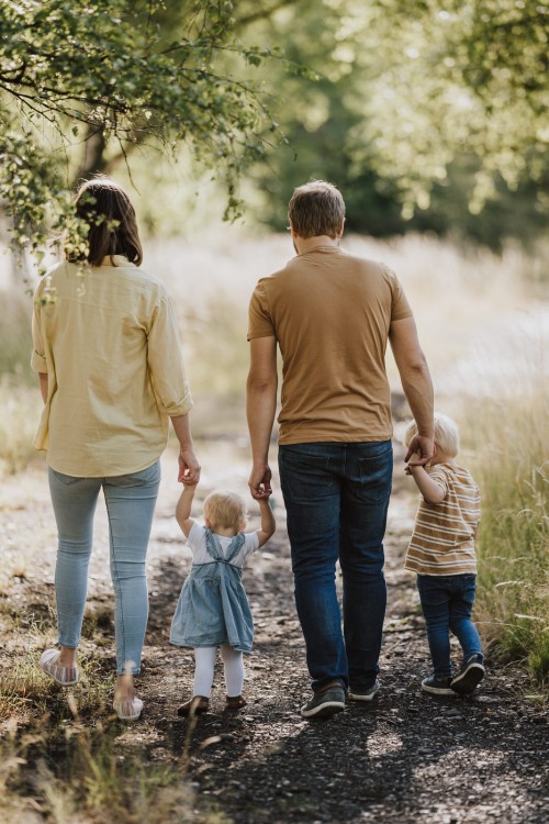 Ein Mann und eine Frau gehen mit beiden Kindern händchenhaltend den Feldweg entlang.