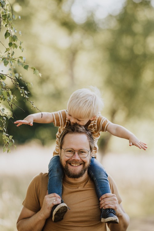 Ein Mann hält ein Kind huckepack.