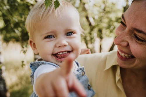 Eine Frau hält ein lächelndes Baby auf dem Arm.
