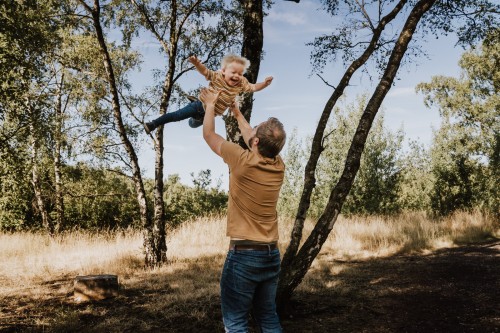Ein Mann wirft einen kleinen Jungen in die Luft.