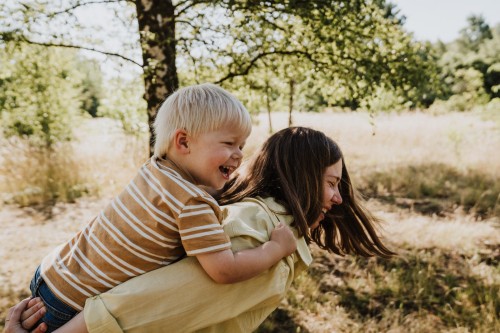 Eine Frau hält einen kleinen Jungen huckepack.