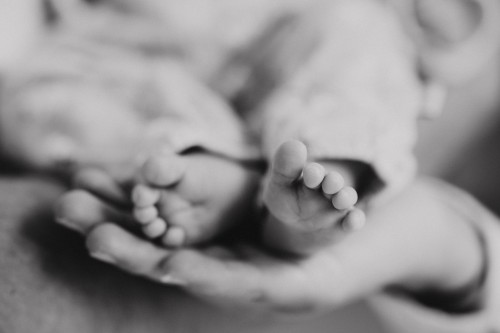 Kleine Babyfüße gehalten von einer großen Hand.