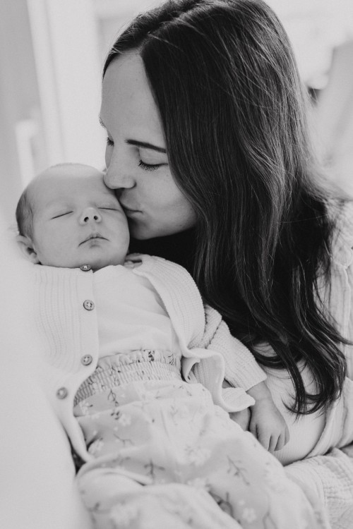 Eine Frau küsst ein kleines Baby am Kopf.