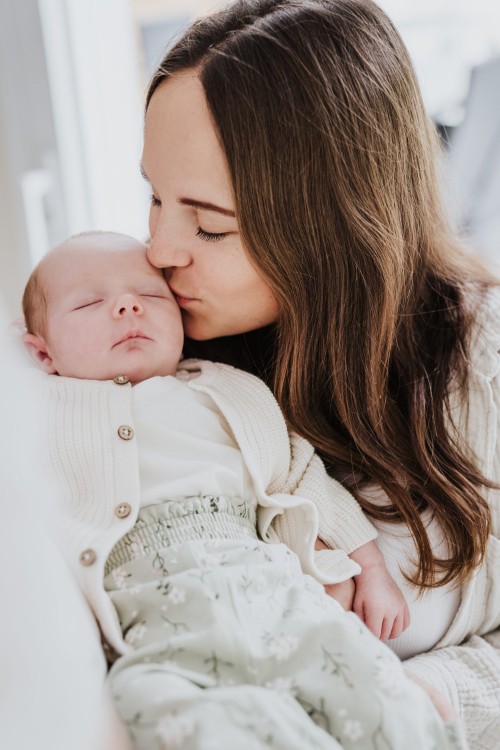 Eine Frau küsst ein kleines Baby am Kopf.