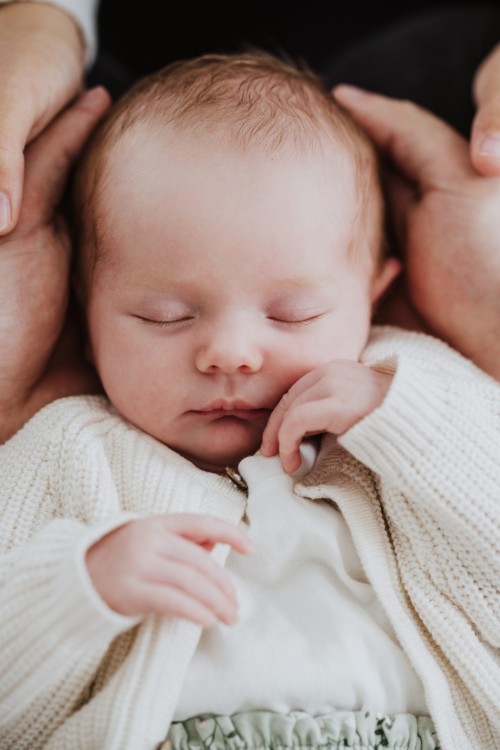 Ein kleines Baby liegt in den Händen von seinen Eltern.