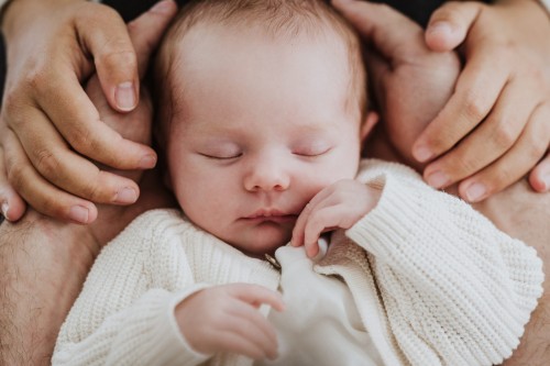 Ein kleines Baby liegt in den Händen von seinen Eltern.