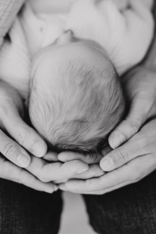 Ein kleines Baby liegt in den Händen von seinen Eltern.