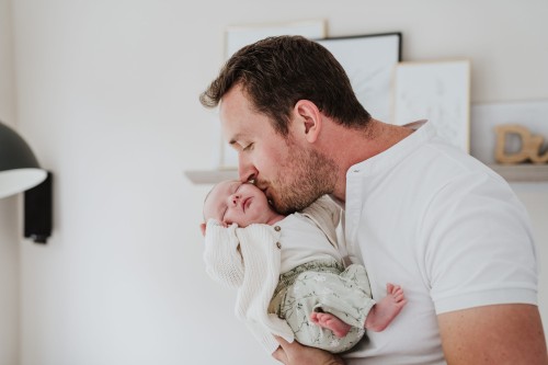 Ein Mann gibt seinem Baby ein Kuss auf die Wange.